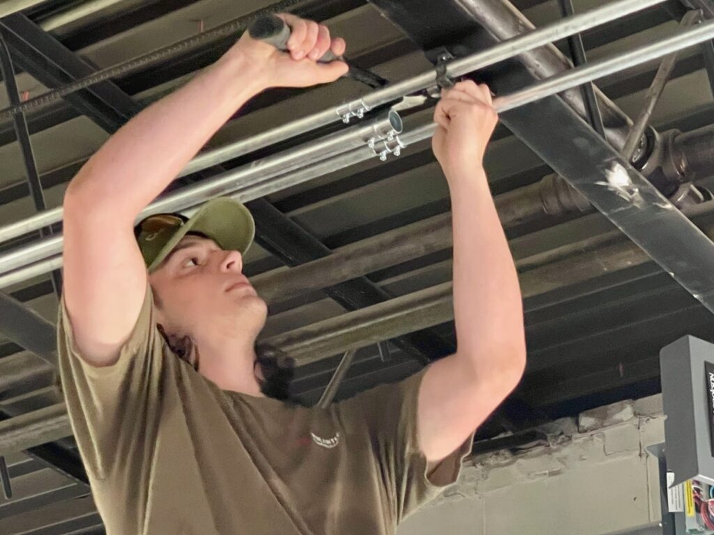 Isaac Arnold, third-year electrician apprentice, working on ceiling conduit.