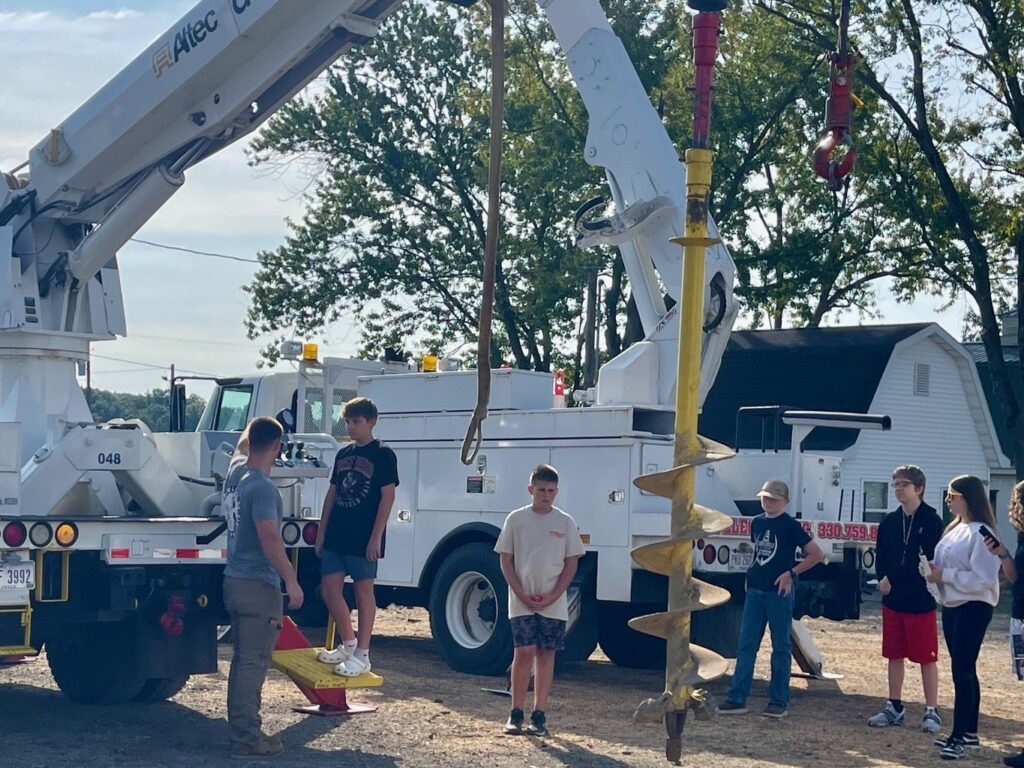 Electrician apprentice shows middle school students at the Mahoning Valley Skilled Trades Expo what a digger truck can do. They also learned about bucket trucks.