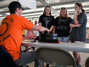 Students are shown an example electrical project by an instructor. 