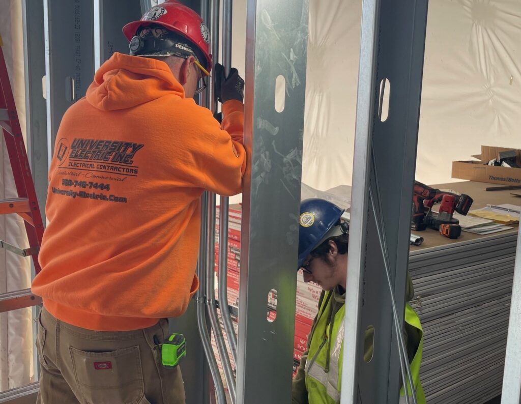 Electricians running wiring for walls of hospital.