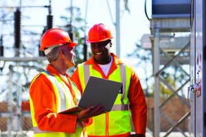 electricians using laptop computer in substation