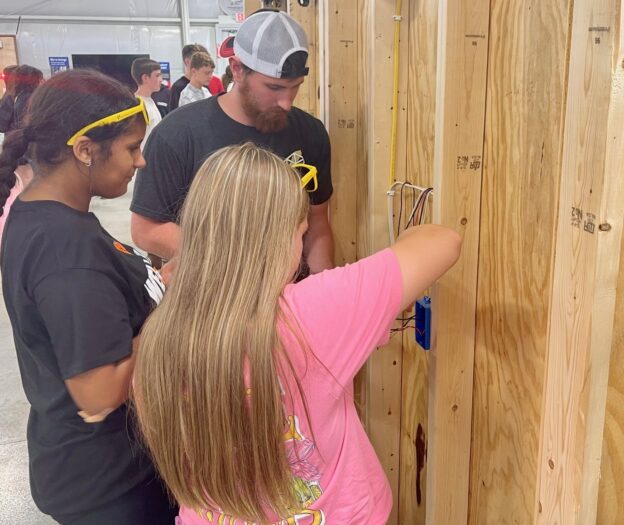 Middle school students working with apprentice at residential wiring demonstration.